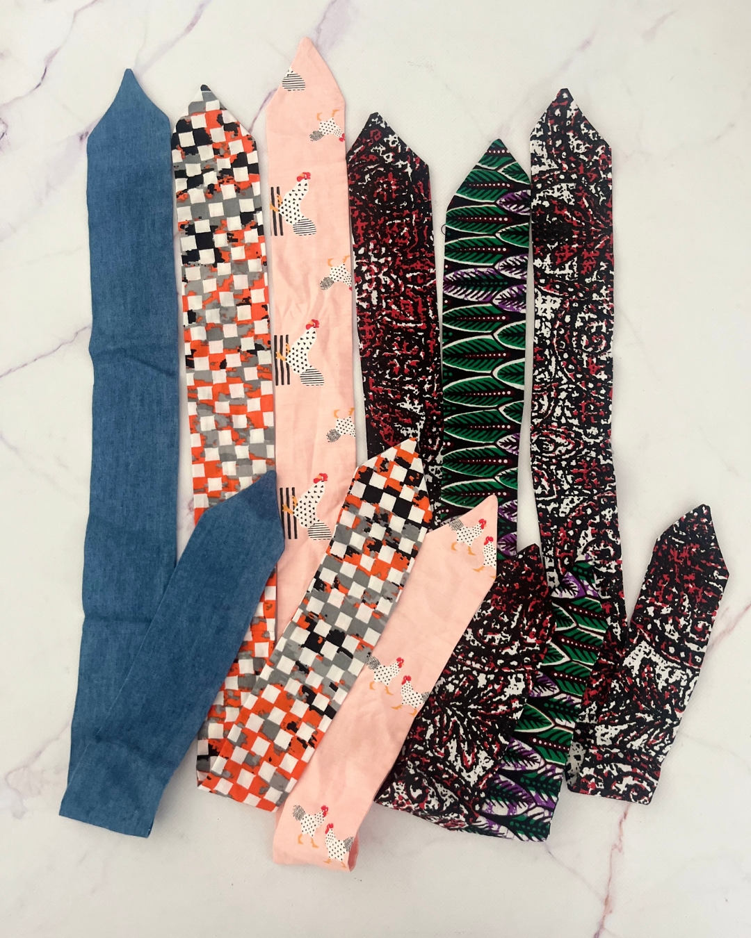 Assorted headbands in denim, orange checks, pink chicken, black and red pattern (2) and green/purple ferns